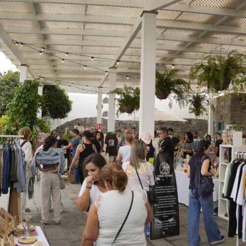 Visitantes disfrutando de los puestos de la 5ª Edición de Arucas es Arte, rodeando los stands con productos y actividades creativas